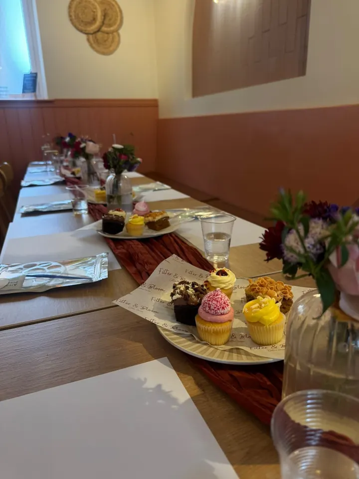 A table laid for a paint night with cupcakes, fresh flowers and painting kits